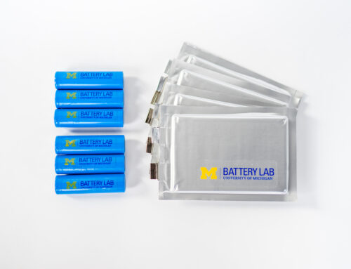 Blue U-M Battery Lab branded batteries arranged next to a splayed layer of gray U-M Battery Lab branded packets